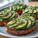 Festive shamrock-shaped avocado slices topped with everything bagel seasoning on whole grain toast, perfect for St. Patrick's Day brunch.