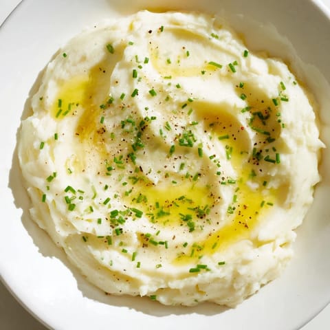 A generous bowl of creamy mashed potatoes, garnished and ready to enjoy with a family meal.