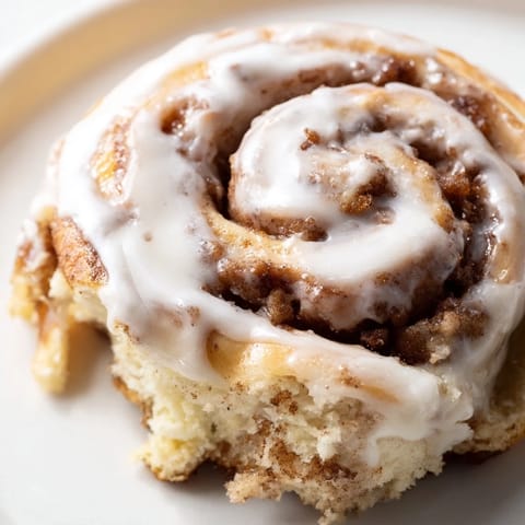 Homemade cinnamon rolls, showing tender spirals, fragrant cinnamon, and a sweet, creamy glaze drizzled.