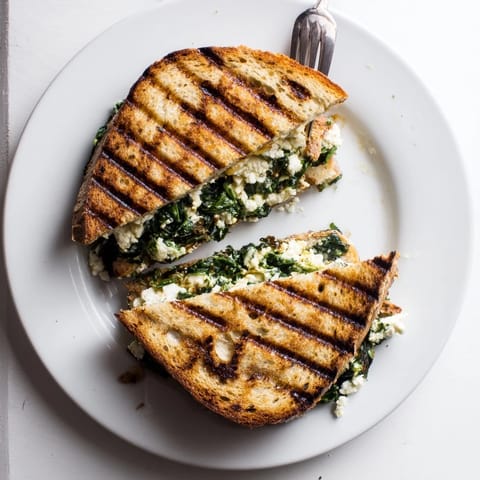 Golden-brown Feta & Spinach Stuffed Grilled Cheese oozing melted cheese, served with tomato soup.