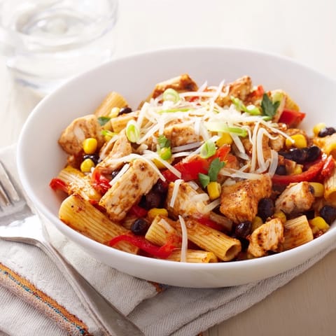 A close-up of Crispy Chicken Burrito Pasta topped with fresh cilantro and green onions, steam rising from the melted cheese.  