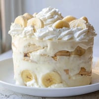 A layered bowl of creamy banana pudding with fresh banana slices and wafers.